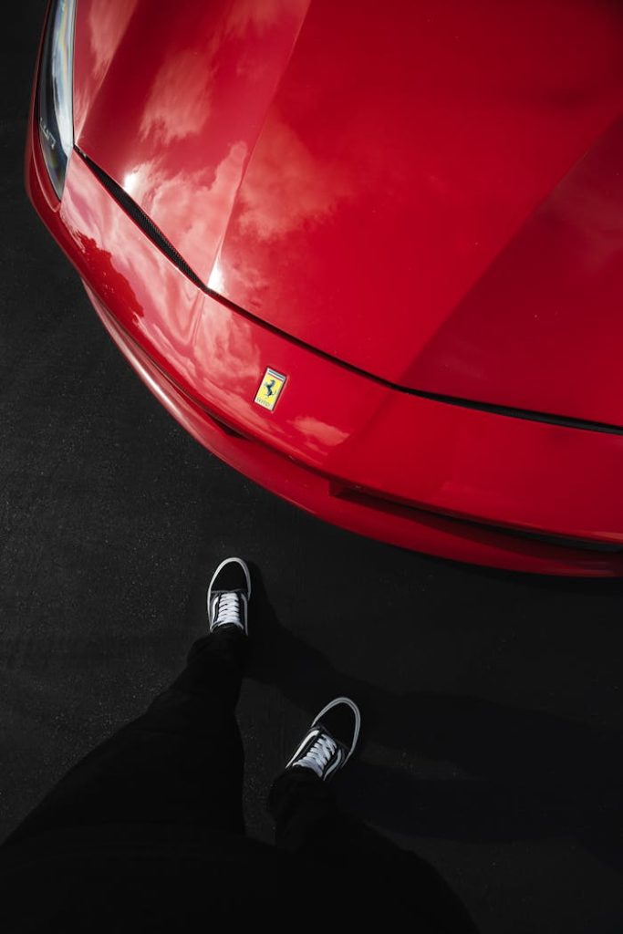 The Art of Drawing Readers In: Your attractive post title goes here Dramatic vertical shot of a red luxury car with sneakers visible, emphasizing style and elegance.