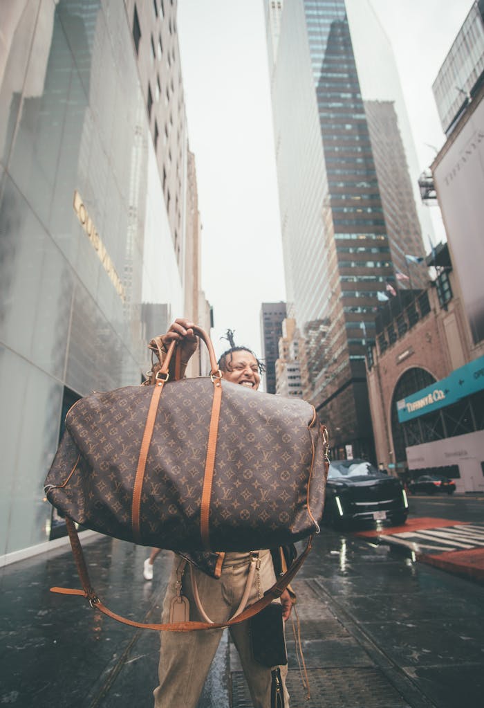 Menus Person holding a large luxury bag on a rainy New York City street.